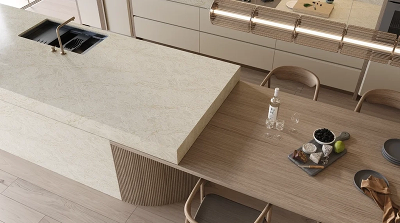 Modern kitchen with marble island, wood dining table, chairs, fruit bowl, and water bottle.